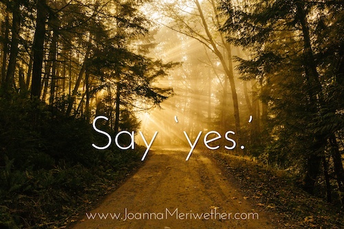 a road that is partly in darkness heading towards sunlight with the words 'say yes' across the pathway